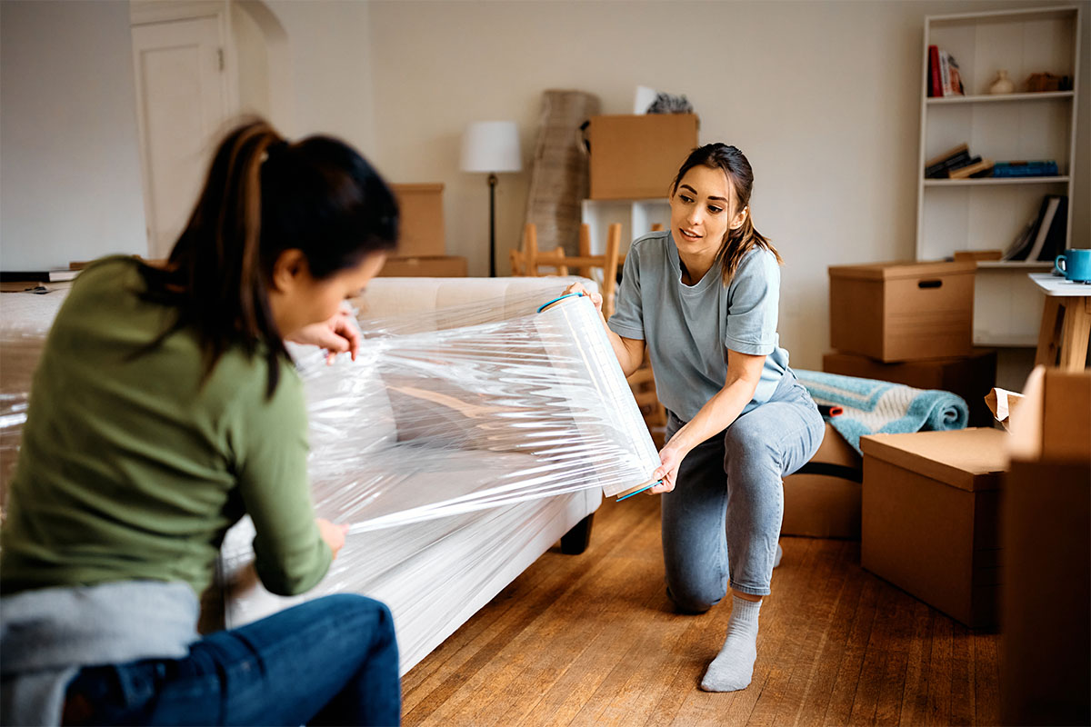 Young women wrapping furniture on their moving day.