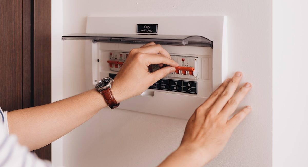 Circuit breaker board displays many switches. A finger is about to turn it back on