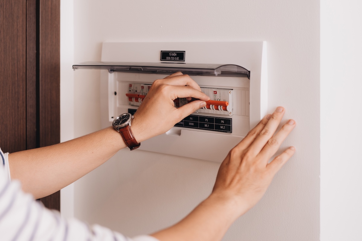 Circuit breaker board displays many switches. A finger is about to turn it back on